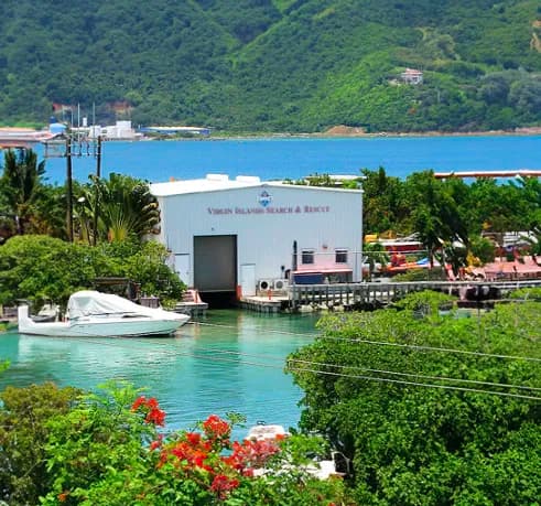 Large silver building with plaque like finishing, a large flagpole out front with cars.