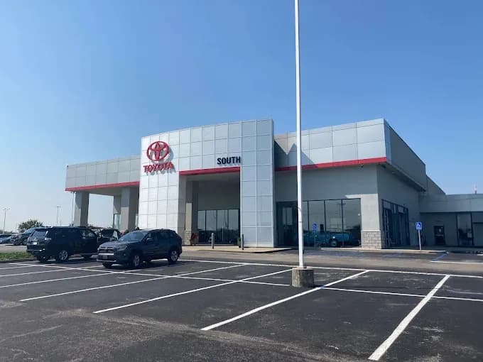 Large silver building with plaque like finishing, a large flagple out front with cars.